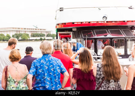 Washington DC, USA - August 4, 2017: Many people standing in Georgetown park on riverfront in evening with potomac river, DC Cruises boat and Kennedy  Stock Photo