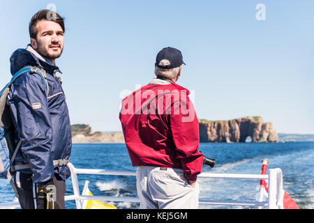 Perce, Canada - June 6, 2017: People tourists on boat tour taking photo picture of Rocher Perce rock in Gaspe Peninsula, Quebec, Gaspesie region Stock Photo