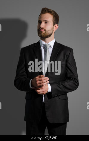Portrait of young businessman standing in studio, on dark background concept Stock Photo