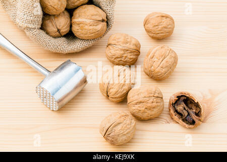 Walnuts kernels and whole walnuts on wooden background. Whole and chopped walnuts on wooden background. Walnuts kernels and nutcracker. Selective focu Stock Photo