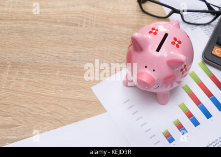 Pink piggy bank with graph and calculator on wooden desk - growing interest rate concept Stock Photo