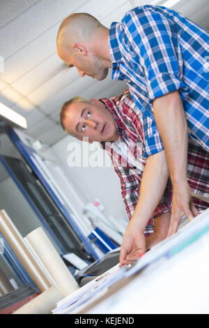 two architects discussing details of blueprint Stock Photo