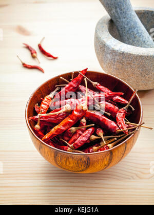 Dried Chillies on white wooden background with mortar and pestle. Selective focus depth of field. Stock Photo