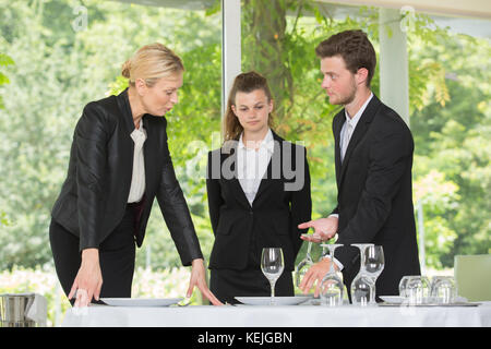 team of waiters setting a table in restaurant Stock Photo