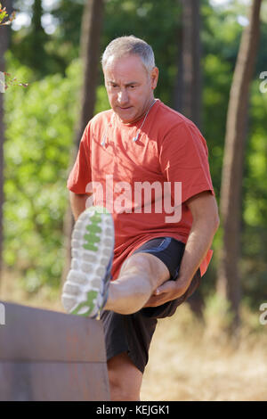 handsome middle aged man stretching leaning on bench Stock Photo