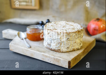 Homemade Shropshire Blue cheese on wooden board with grapes and jam Stock Photo