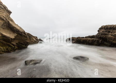 Rocky Malibu beach with motion blur water. Stock Photo