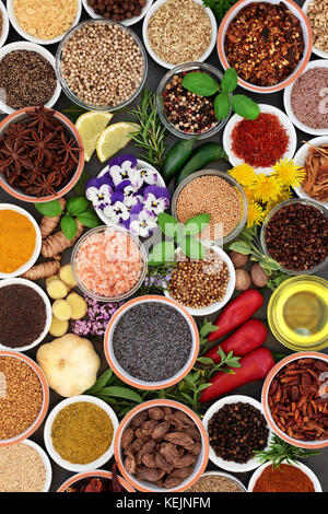 Herb, spice and edible flower selection in bowls and loose forming a colorful abstract background. Top view. Stock Photo