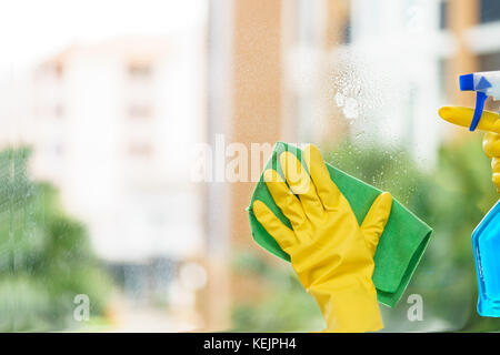 Housekeeper cleaning mirror with green cloth. Stock Photo