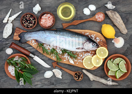 Rainbow trout health food on an olive wood board with seasoning. Very high in omega 3 fatty acid and beneficial to maintain a healthy heart. Stock Photo