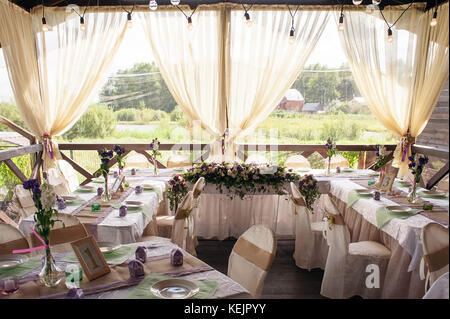 Beautifully decorated table for the wedding ceremony. Served banquet table decorated with fresh flowers in the open air. Stock Photo