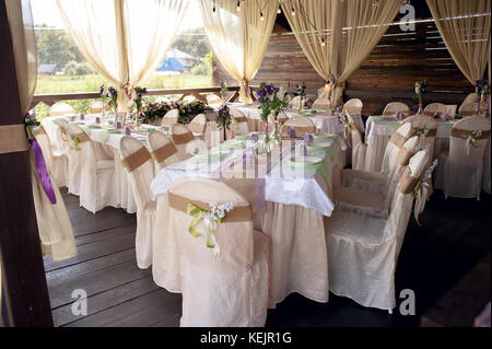Beautifully decorated table for the wedding ceremony. Served banquet table decorated with fresh flowers in the open air. Stock Photo