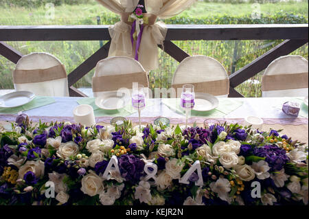 Beautifully decorated table for the wedding ceremony. Served banquet table decorated with fresh flowers in the open air. Stock Photo