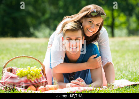 Portrait Of Happy Young Couple Laying On Blanket In Park Stock Photo