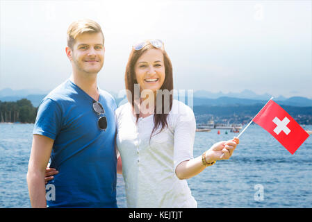 Portrait Of Happy Young Couple Holding Swiss Flag Stock Photo