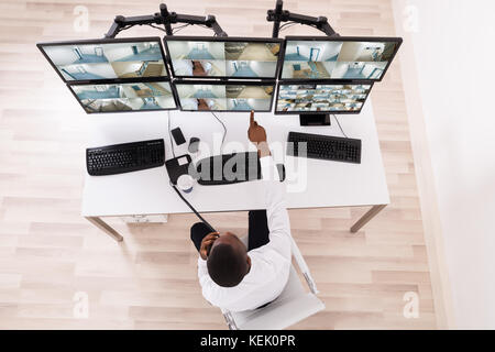 High Angle View Of Male Operator Pointing At CCTV Footage On Computer Stock Photo