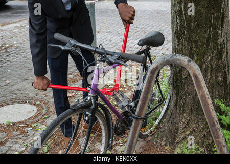 Thief Trying To Break The Bicycle Lock With Long Pliers Stock Photo