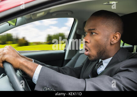 Shocked Young Businessman With Mouth Open Driving Car Stock Photo