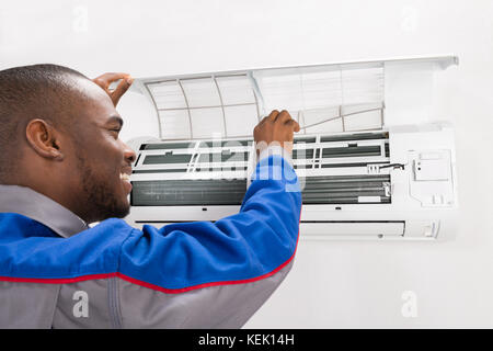 Happy Male Technician Checking Air Conditioner At Home Stock Photo