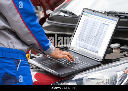 Close-up Of Male Mechanic Using Laptop For Examining Car Engine Stock Photo