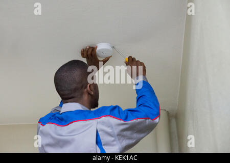 Young Male Electrician Installing Fire Sensor On A Ceiling Stock Photo