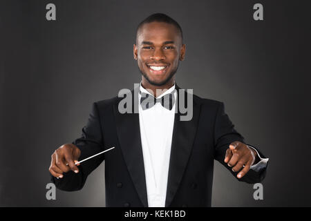 Portrait Of Happy Music Conductor With Baton Against Black Background Stock Photo