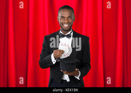 Young Happy Magician Showing Trick With Playing Cards Stock Photo