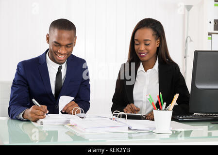 Two Happy Businesspeople Working On Business Document At Office Stock Photo