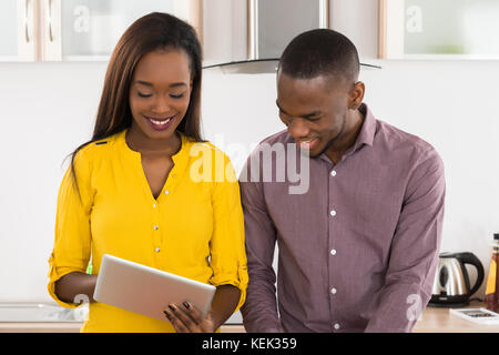 Young African American Couple Using Digital Tablet In Kitchen For Recipe Stock Photo