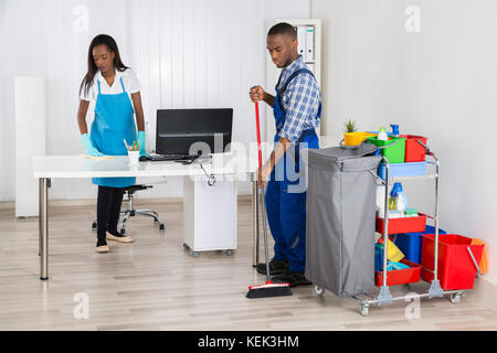 Young African Male And Female Cleaners Cleaning Office Stock Photo