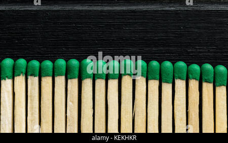 Many green tip wood matches in a row, single line, with a black background, texture and pattern Stock Photo