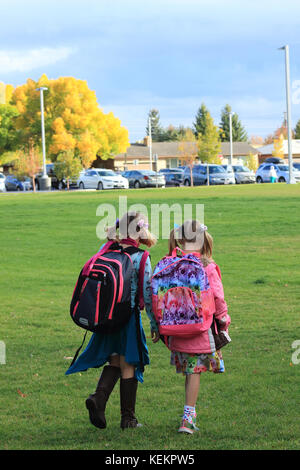 Young girls walking across a school playground fall colors in Idaho Falls, Idaho, USA Stock Photo