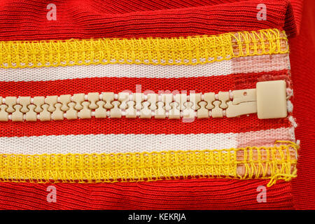 Closeup of a white zipper on a red blouse. Stock Photo