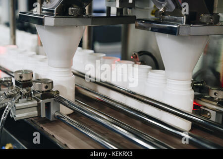 white plastic bottles on the production line of the conveyor at filling machine in the factory. selective focus. Stock Photo