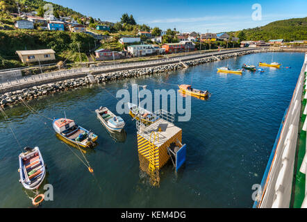 Boats at wharf and houses in Puerto Aguirre, view from a ferry, at Isla Las Huichas, Islas Huichas archipelago, Patagonia, Chile Stock Photo