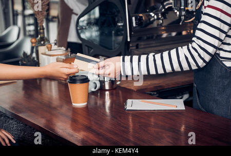 customer pay coffee drink with credit card to barista,Close up hand paid for to go coffee cup at counter bar in cafe,Food and drink business,billing p Stock Photo