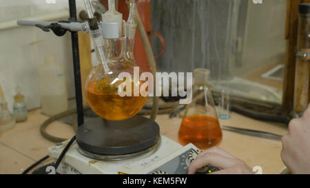 Scientist mixing liquids in flasks in a research lab. Special equipment for mixing fluids in lab. Intern mixing reactants together in the flask. Stock Photo