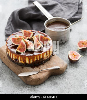 Cake with fresh figs and salted caramel on wooden serving board over grunge background Stock Photo