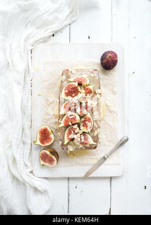 Loaf cake with figs, almond and white chocolate on wooden serving board over light background Stock Photo