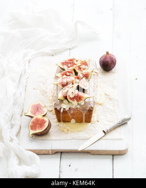 Loaf cake with figs, almond and white chocolate on wooden serving board over grunge background, selective focus. Stock Photo