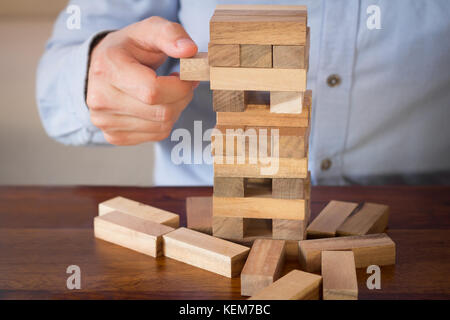 hand of businessman pulling out or placing wood block on the tower Stock Photo