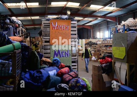 Embargoed to 0001 Monday October 23 Volunteers sort donations at a warehouse in Calais where charities including Help Refugees and Care4Calais are providing food, clothing and personal hygiene items to migrants around the town, as one year on from the demolition of the camp dubbed 'The Jungle' migrants continue to stay in Calais and attempt to cross the border to the UK. Stock Photo