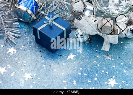 christmas tree decorations on blue sparkling background. silver balls, drum and blue small gift box. Stock Photo