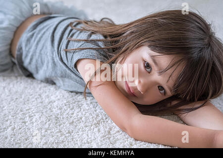 Five year old girl laying on the carpet in her room Stock Photo