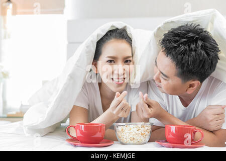 Young Asian Couples having breakfast on bed together in bedroom of contemporary house for modern lifestyle concept Stock Photo