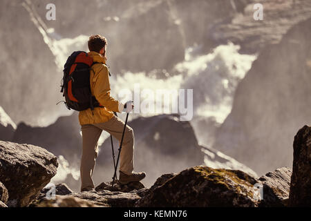 Hiker hiking with backpack looking at waterfall Stock Photo