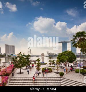 Tourists near the Merlion and looking out over some of the major tourist attractions of Singapore - the Marina Bay Sands, the Art and Science Museum a Stock Photo