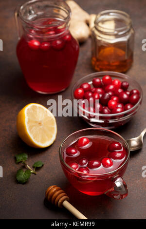 cranberries lemon ginger drink in a glass cup, honey, half a lemon, slices of ginger on a dark background Stock Photo