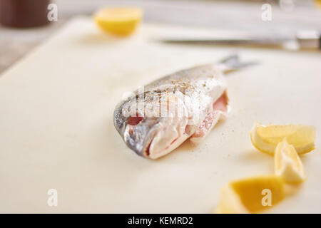 Raw fish with spices and lemon. Fresh fish with lemon on cutting board. Cooking dorado fish. Stock Photo