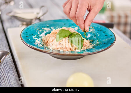 Delicious italian pasta with green basil. Chef hand serving appetizing pasta creama di pollo with cheese and greenery. Cooking and food preparing conc Stock Photo